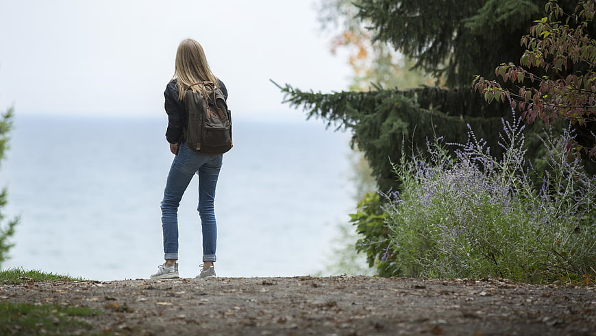 Woman with Backpack Standing by the Sea