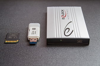 Toshiba USB Drive, Memory Card, and D-LOCK External Hard Drive on Gray Surface