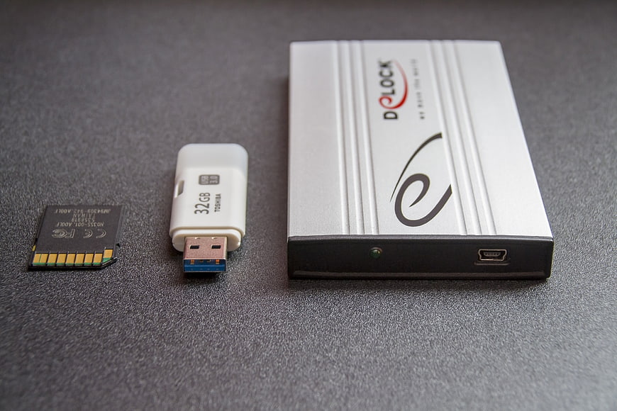 Toshiba USB Drive, Memory Card, and D-LOCK External Hard Drive on Gray Surface