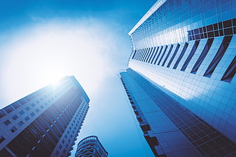 Low angle view of modern glass skyscrapers against blue sky