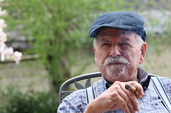 Senior man with mustache smoking cigar outdoors
