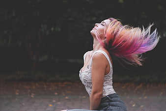 Woman with colorful hair flipping head outdoors