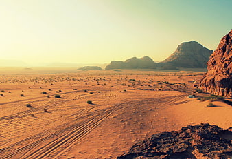 Vast desert landscape with sand dunes and mountains at sunset