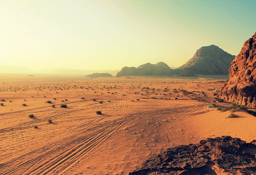Vast desert landscape with sand dunes and mountains at sunset