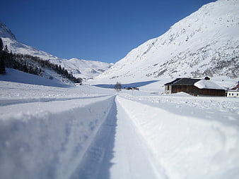 Snowy Mountain Road with Tracks and Barn in Winter