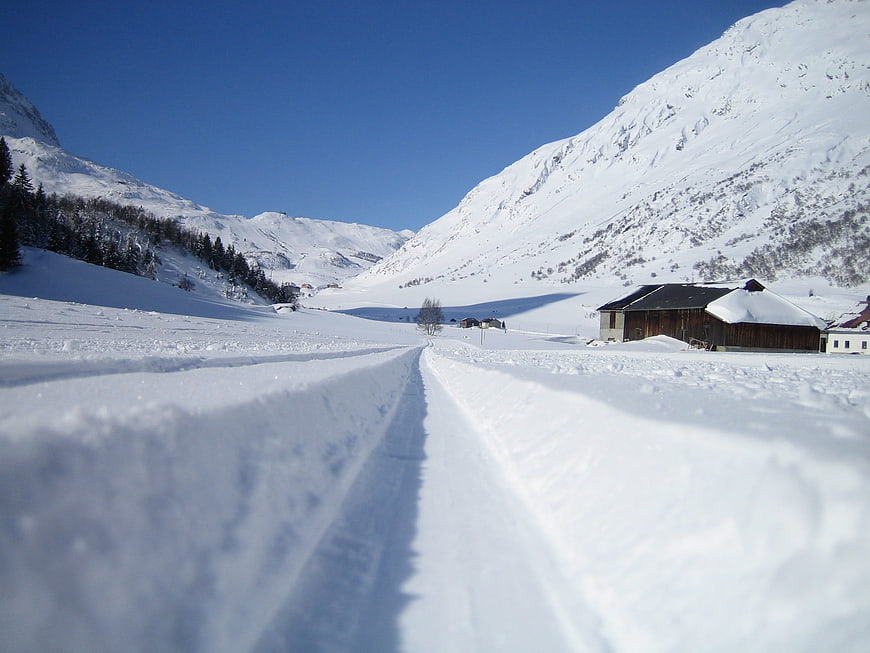 Snowy Mountain Road with Tracks and Barn in Winter