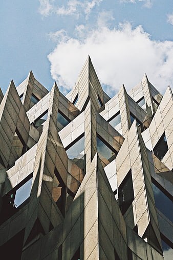 Low angle view of modern geometric architecture against blue sky