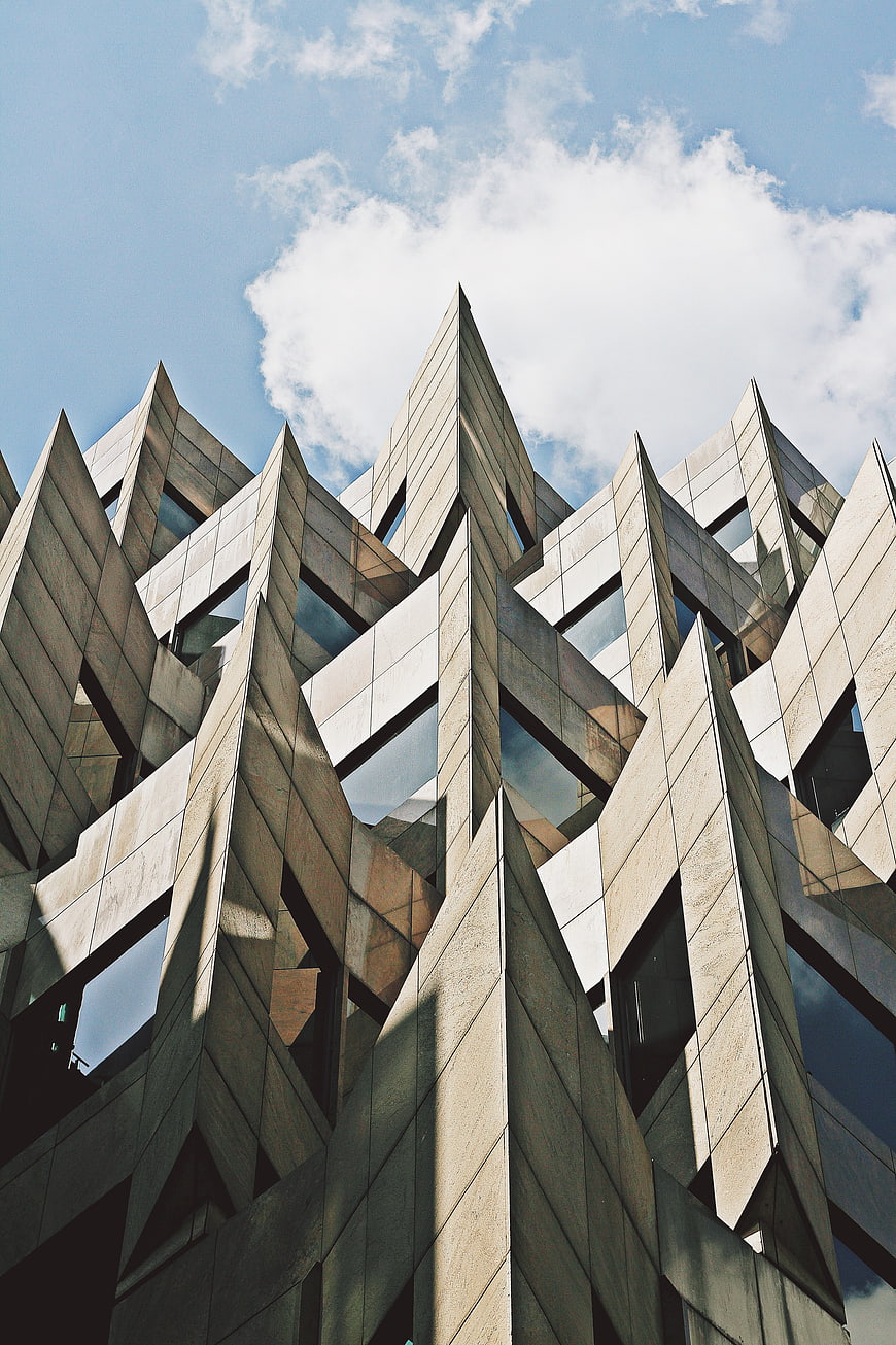 Low angle view of modern geometric architecture against blue sky