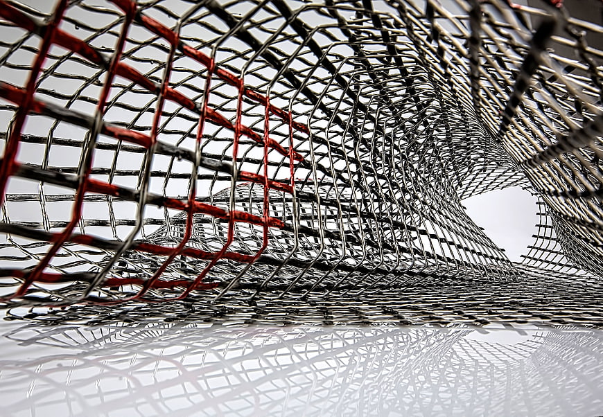 Abstract Metal Mesh Sculpture with Red Accents and Reflection