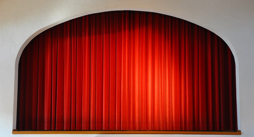 Red theater curtain in arched stage opening