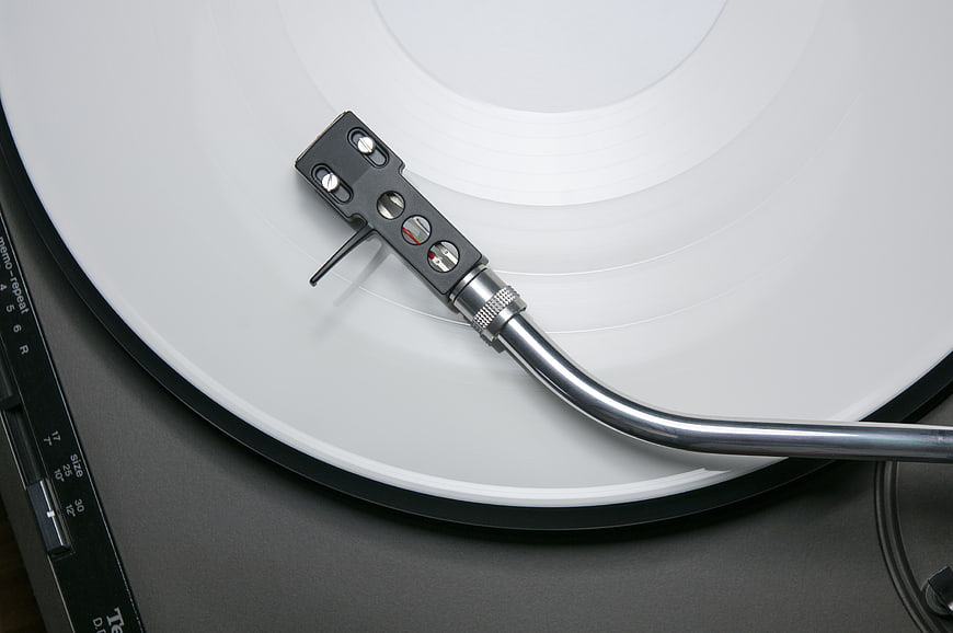 Close-up of turntable tonearm on white vinyl record