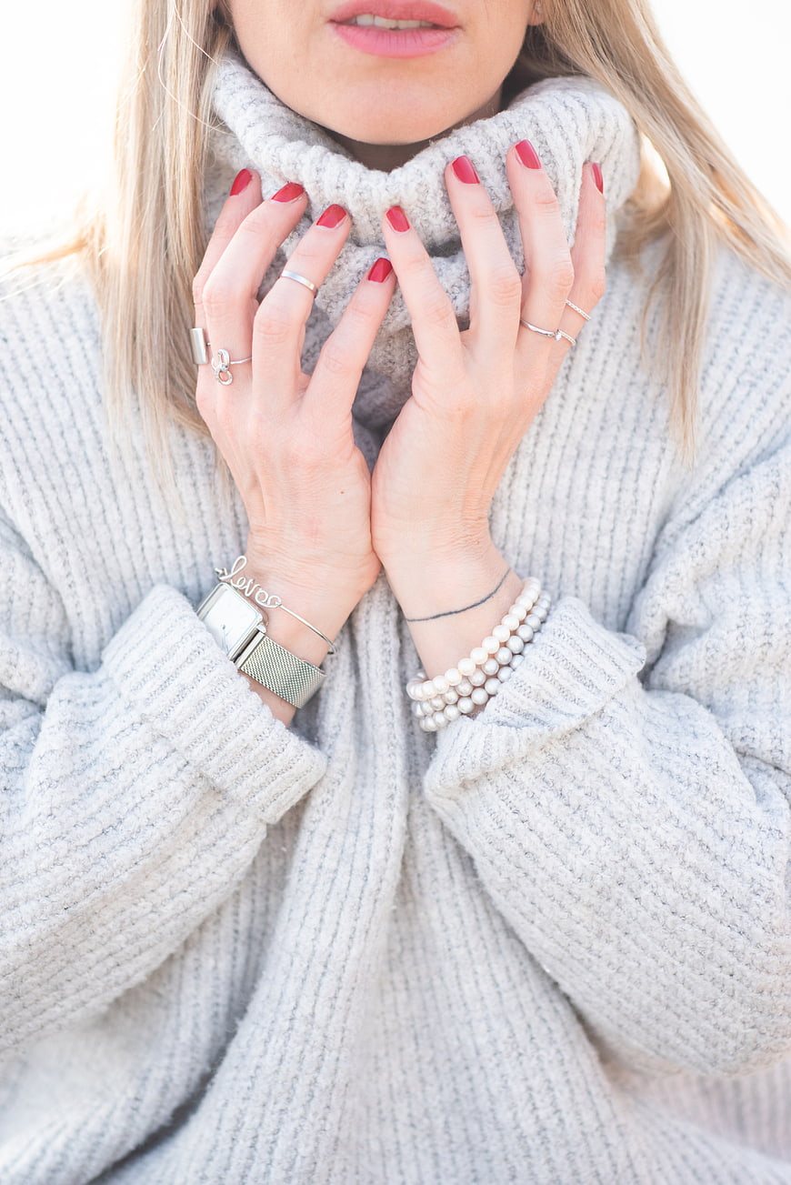 Woman in Grey Sweater with Red Nails and Jewelry