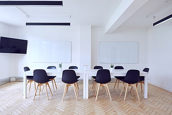 Modern minimalist conference room with white tables and black chairs