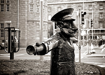 Black and White Statue of Man Pointing in City Street
