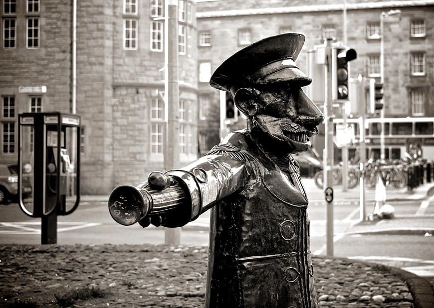 Black and White Statue of Man Pointing in City Street