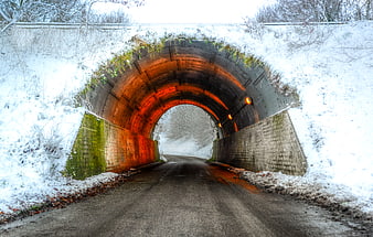 Snowy Road Entering Brick Tunnel with Orange Lights