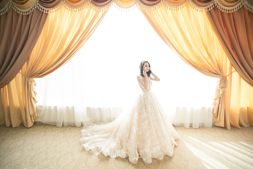 Elegant Bride in Lace Gown by Golden Curtains
