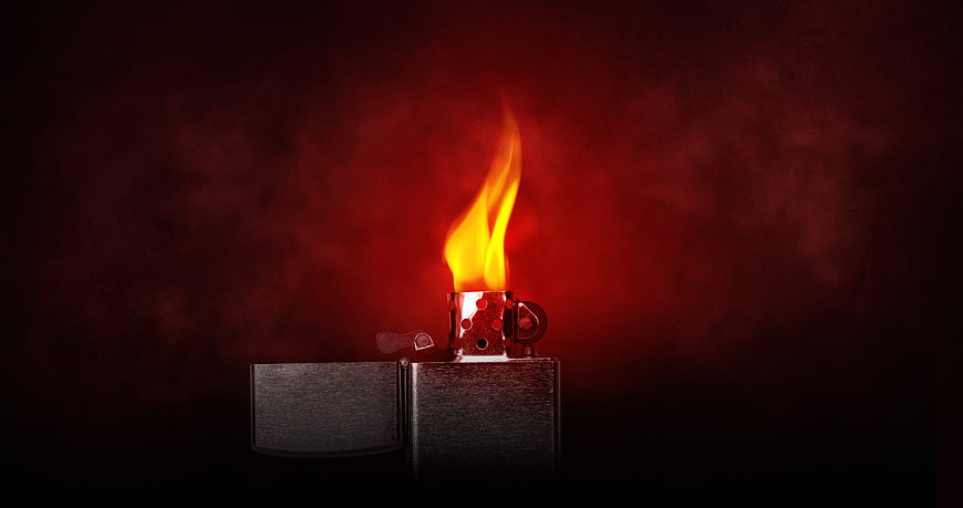 Lit Zippo Lighter with Bright Flame on Dark Red Background