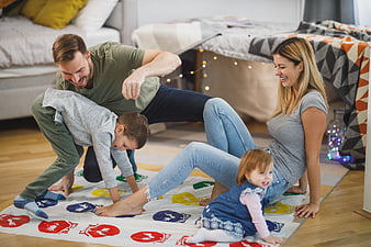Happy family playing Twister game on living room floor