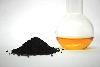 Black Cumin Seeds And Oil In Glass Flask On White Background
