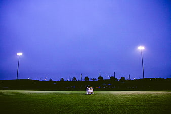 Soccer Team Huddle on Field Under Stadium Lights at Night