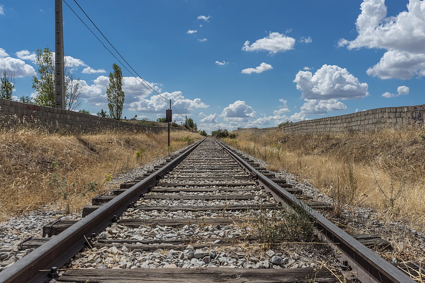 Railway tracks leading to horizon under blue sky