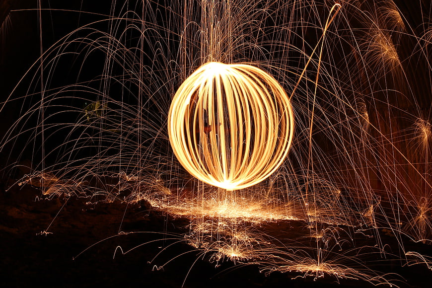 Long exposure steel wool fire spinning art with sparks