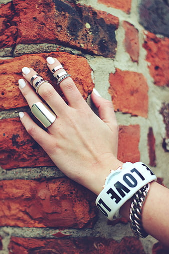 Fashionable hand with rings and bracelet on brick wall