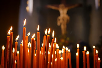 Lit prayer candles in a church with blurred crucifix background