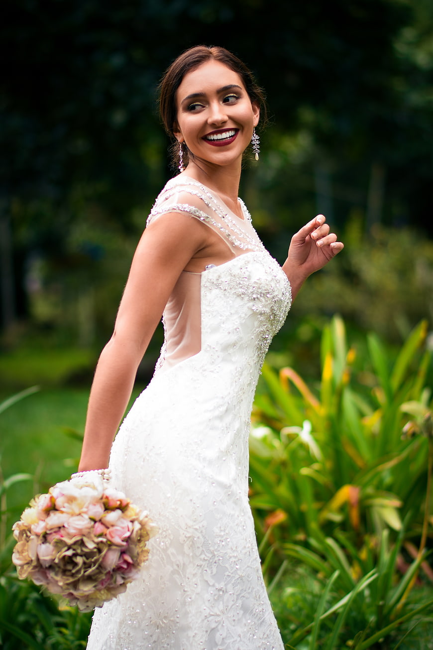 Happy Bride in Beaded Wedding Dress Holding Bouquet