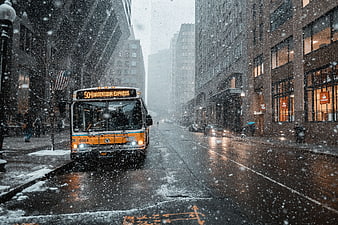 City bus driving on wet street during heavy snowfall