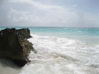 Turquoise ocean waves crashing against dark coastal rocks