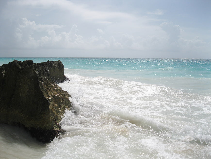 Turquoise ocean waves crashing against dark coastal rocks