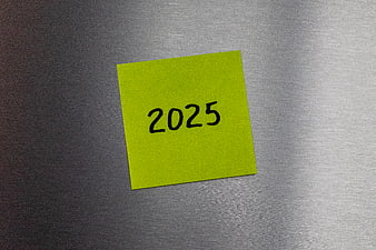 Yellow sticky note with 2025 on metal background
