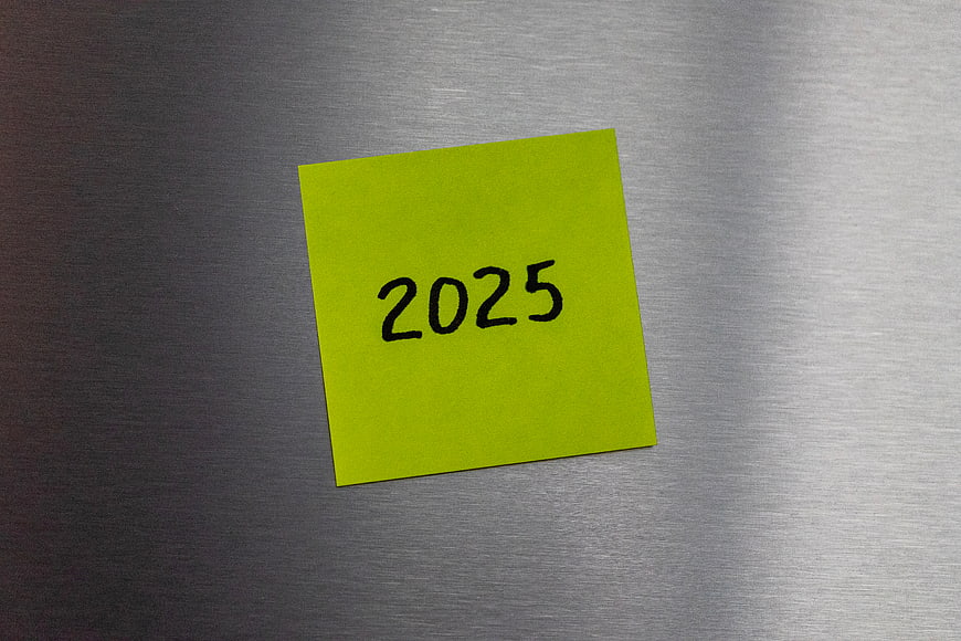 Yellow sticky note with 2025 on metal background