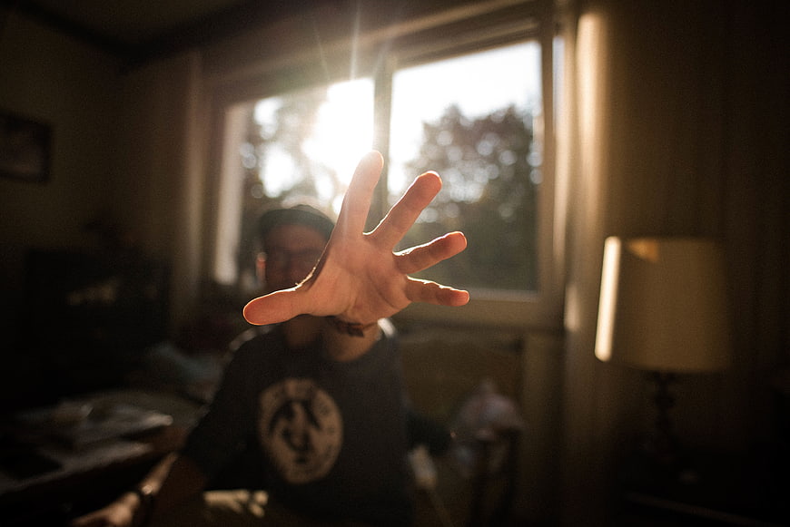 Man Reaching Hand Towards Camera in Sunlit Room
