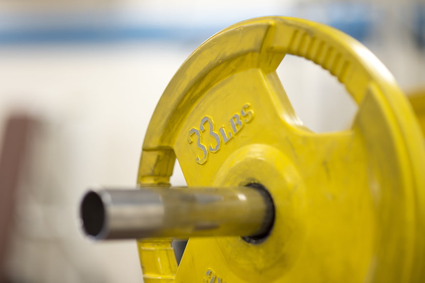 Close-up of yellow 33 lbs weight plate on barbell
