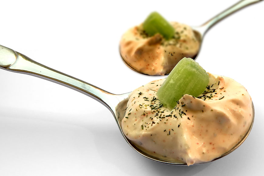 Creamy dip with celery on silver spoons