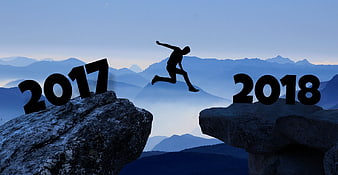 Silhouette of man jumping between 2017 and 2018 on mountain rocks