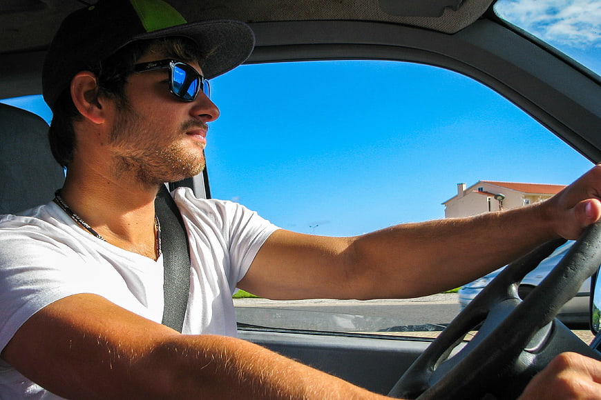 Young man driving car with sunglasses and cap