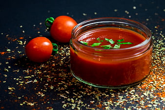 Glass jar of red tomato sauce with fresh tomatoes and herbs