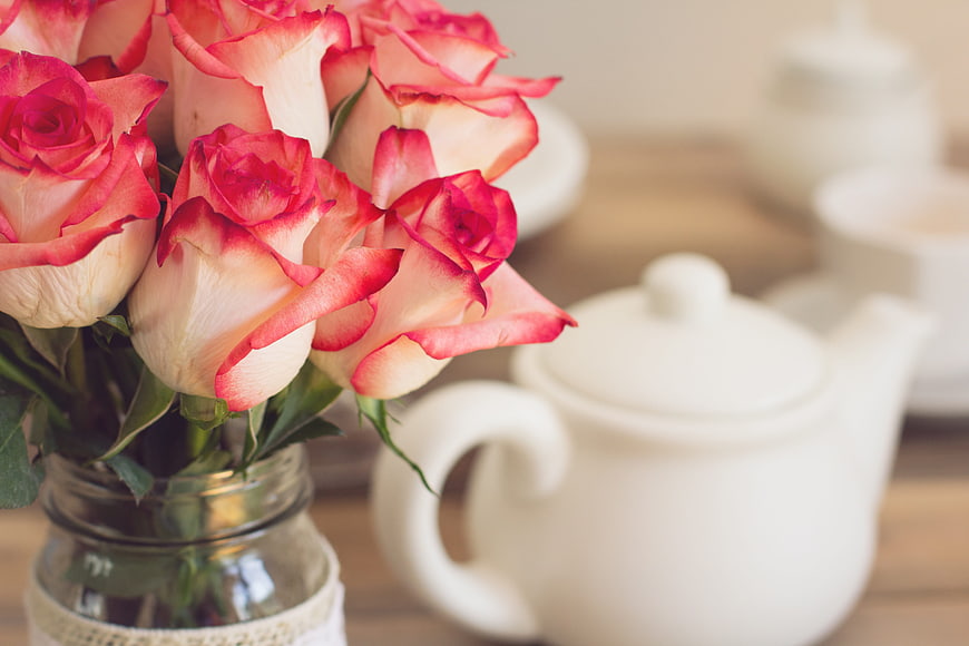 Pink and white roses in a mason jar with a white teapot
