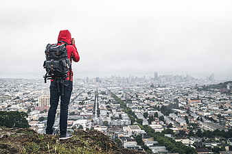 Photographer with Backpack Overlooking Hazy City Skyline