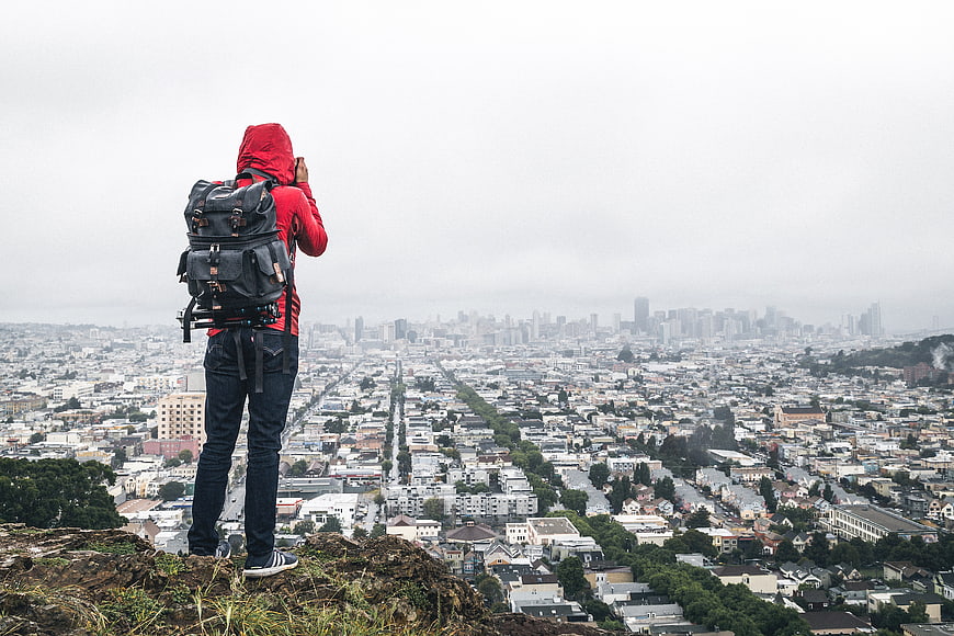 Photographer with Backpack Overlooking Hazy City Skyline