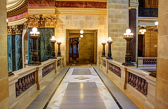 Luxurious marble hotel hallway with ornate lamps and stone walls