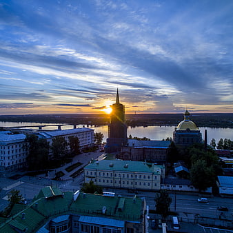Sunset over city skyline with church spire and river