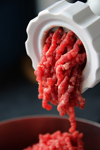 Fresh ground beef extruding from a white manual meat grinder