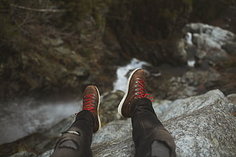 First-person view of hiking boots dangling over a rocky stream