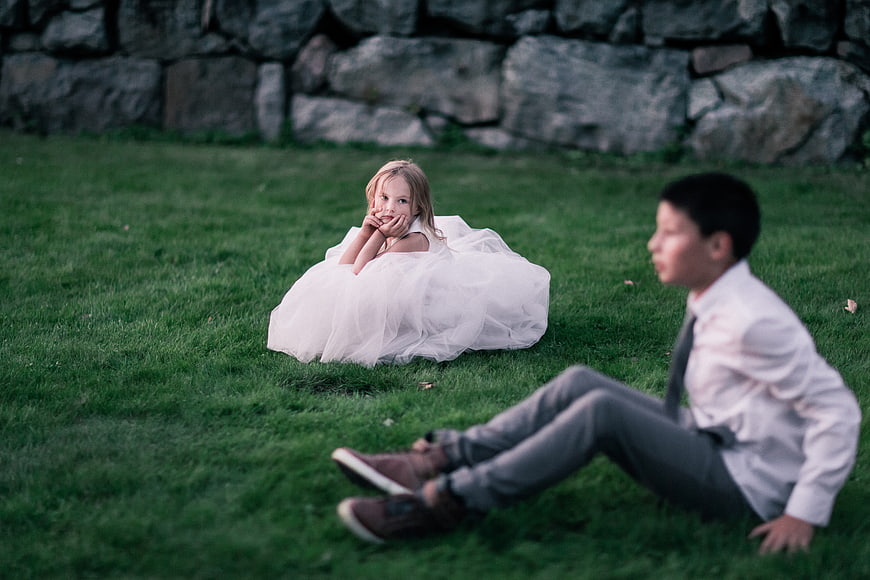 Young girl in white dress and boy in suit on grass