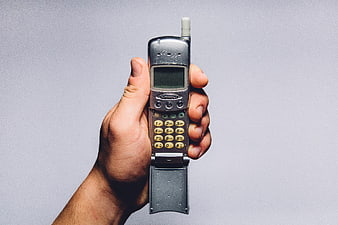 Hand holding vintage silver flip phone with antenna